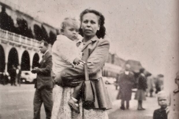 A black and white photograph of Victorias nan holding Victorias dad.