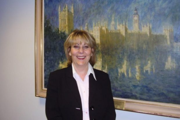 Picture of Loraine, standing in front of a painting of the Houses of Parliament