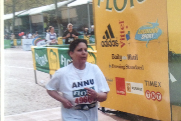 Photo of Andrea crossing the finish line at the London Marathon in 2005. She is passing a banner which lists the sponsors and their logos including Adidas, Vittel, Lucozade Sport, Daily Mail, Evening Standard, Orange, Renault, Timex and TNT