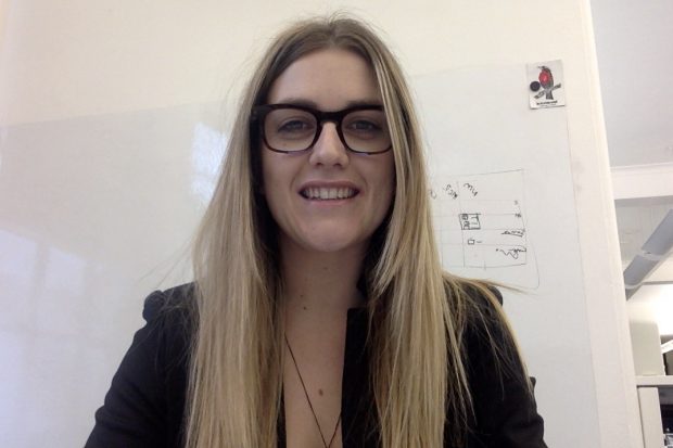 Picture of Regan in the office. Regan has long blonde hair and thick rimmed glasses