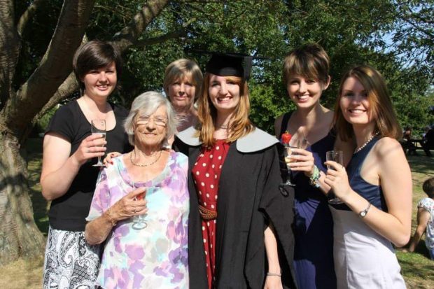Lizz on her graduation day, drinking champagne outside with her gran, mum and three sisters.