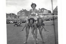 Black and white photo of Ellie's grandmother on top of a human pyramid on the beach