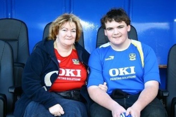 Picture of Alison and her son at a Portsmouth football match. Alison is wearing a red Portsmouth shirt and her son is wearing a blue one.
