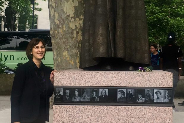 Amirit stands next to the recently- erected statue in Parliament Square. Amrit is wearing a dark suit