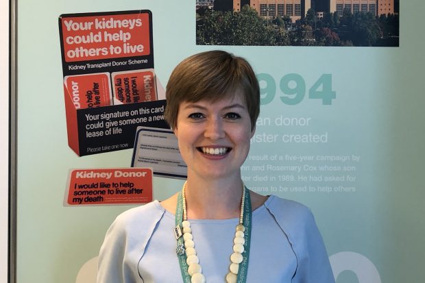 Profile picture of Elaina who is standing in front of an NHS history display.