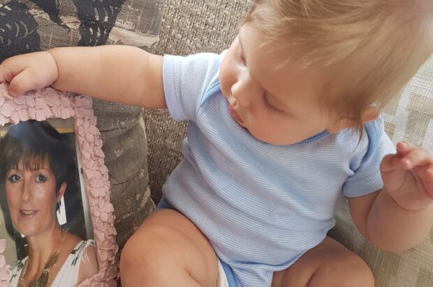 Baby Aurora looking at a photograph of her grandmother in a pink flowery frame