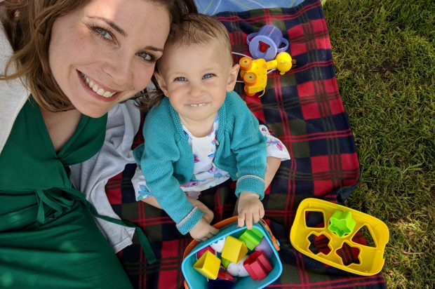 Picture of Liz and her daughter playing with toys on a chequed blanket