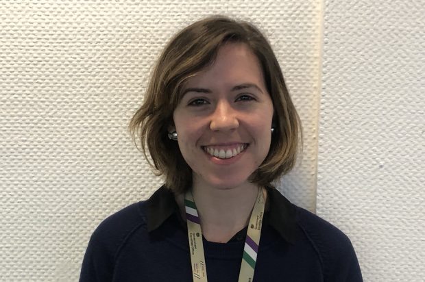 Profile picture of Gillian who is standing in front of a white wall. Gillian has short brown hair and is wearing a gold, purple, white and green suffrage centenary lanyard